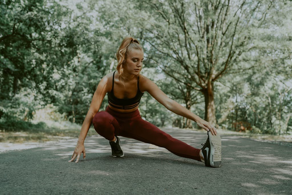Full length of focused female athlete doing lunges forward while stretching legs in park